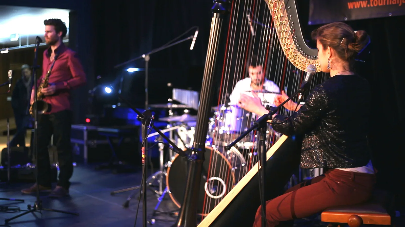 Pia Salvia à la harpe sur scène, avec un saxophoniste et Antoine Valvin à la batterie en arrière-plan