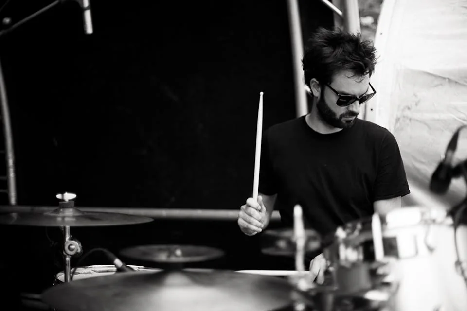 Antoine Valvin jouant de la batterie en concert, photographié en noir et blanc